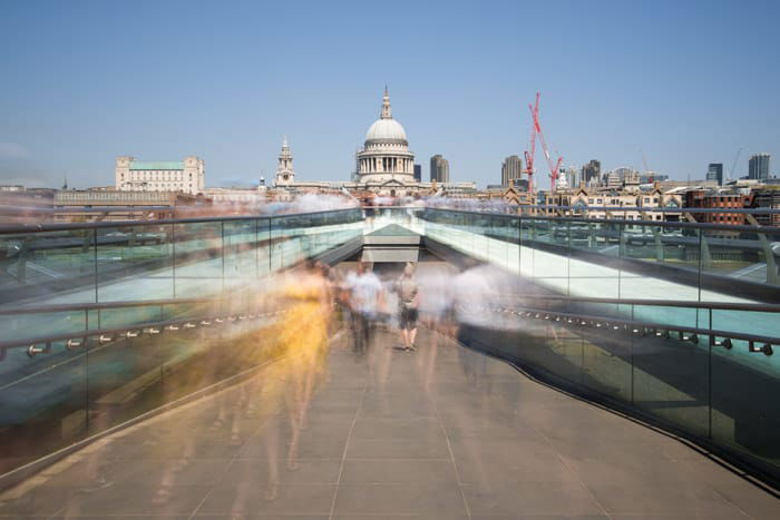 A time lapse photography shot of the blurred figures of people walking out of an underground passage