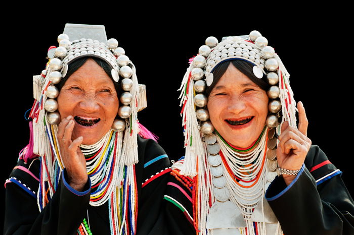 Portrait of two Akha hill tribe women in northern Thailand, posing against a black background for photography.