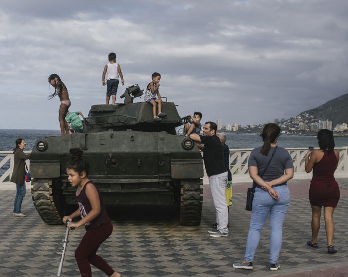 People around and children playing on tank by the sea