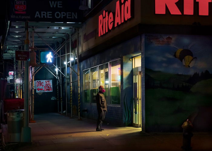 Man standing outside store window at night