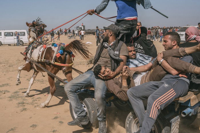 Men on horse-drawn cart carrying wounded man