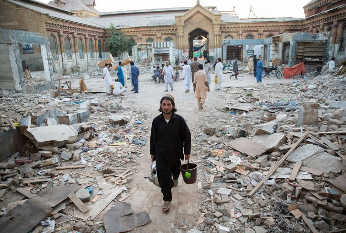 Man carrying rubble in destroyed building