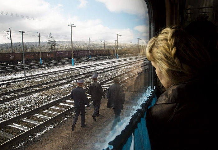 Woman looking out of train window at three men