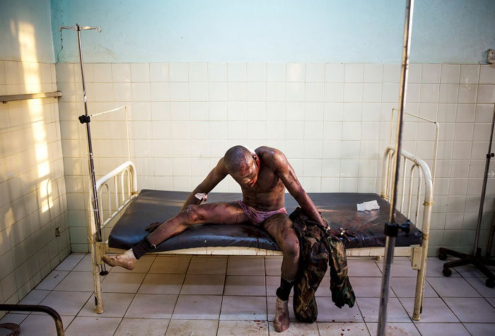 Bloodied man sitting on hospital bed