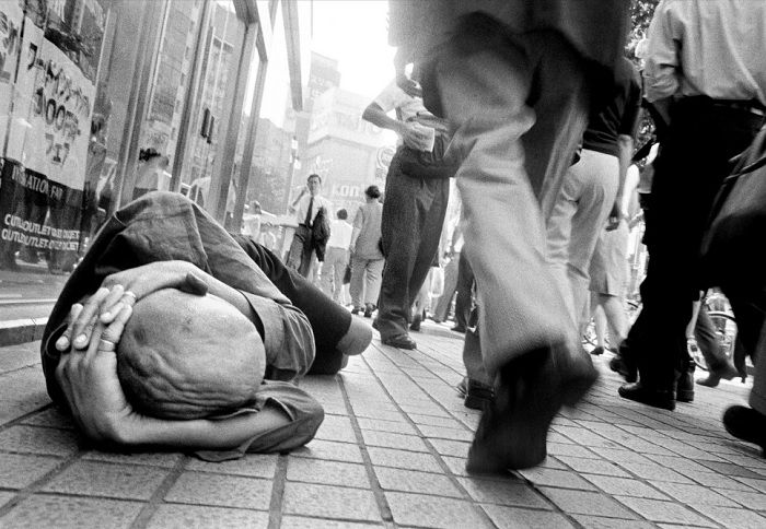 Head on man lying on the street with people walking past