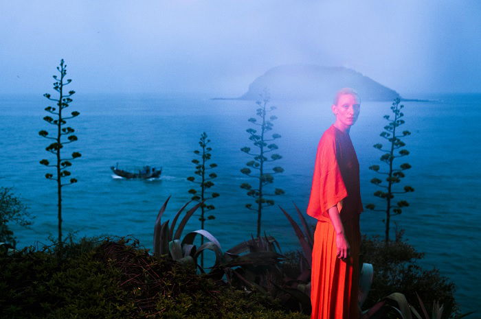 Mysterious image of woman in red near a lake at dusk