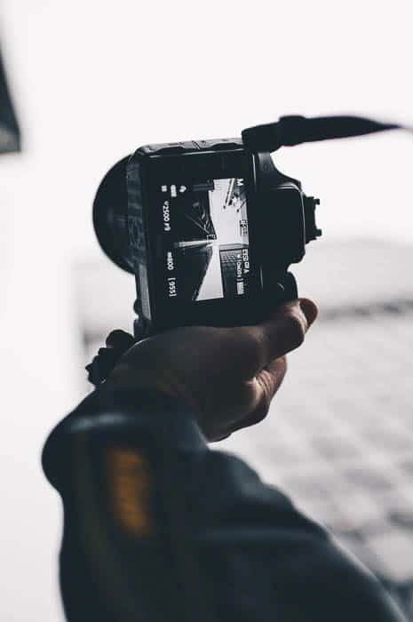 A person holding a dslr camera to take a street photo 