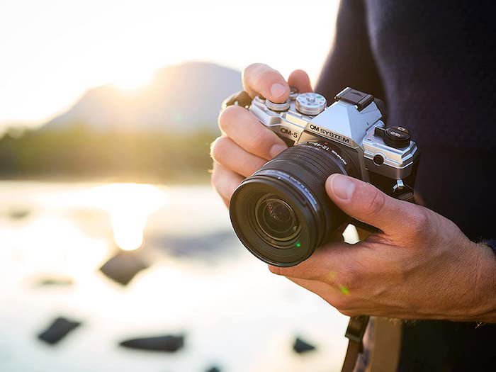 A person holding an OM System OM-5 mirrorless camera