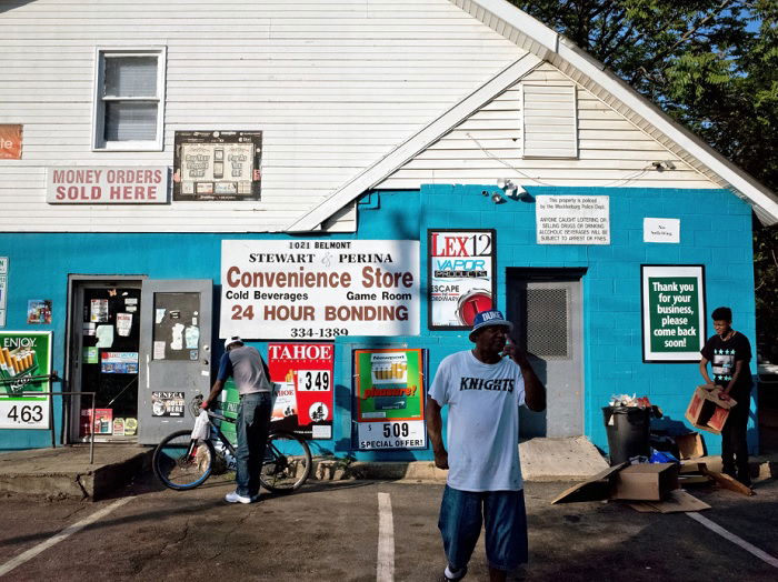 Several men pottering about outside a convenience store